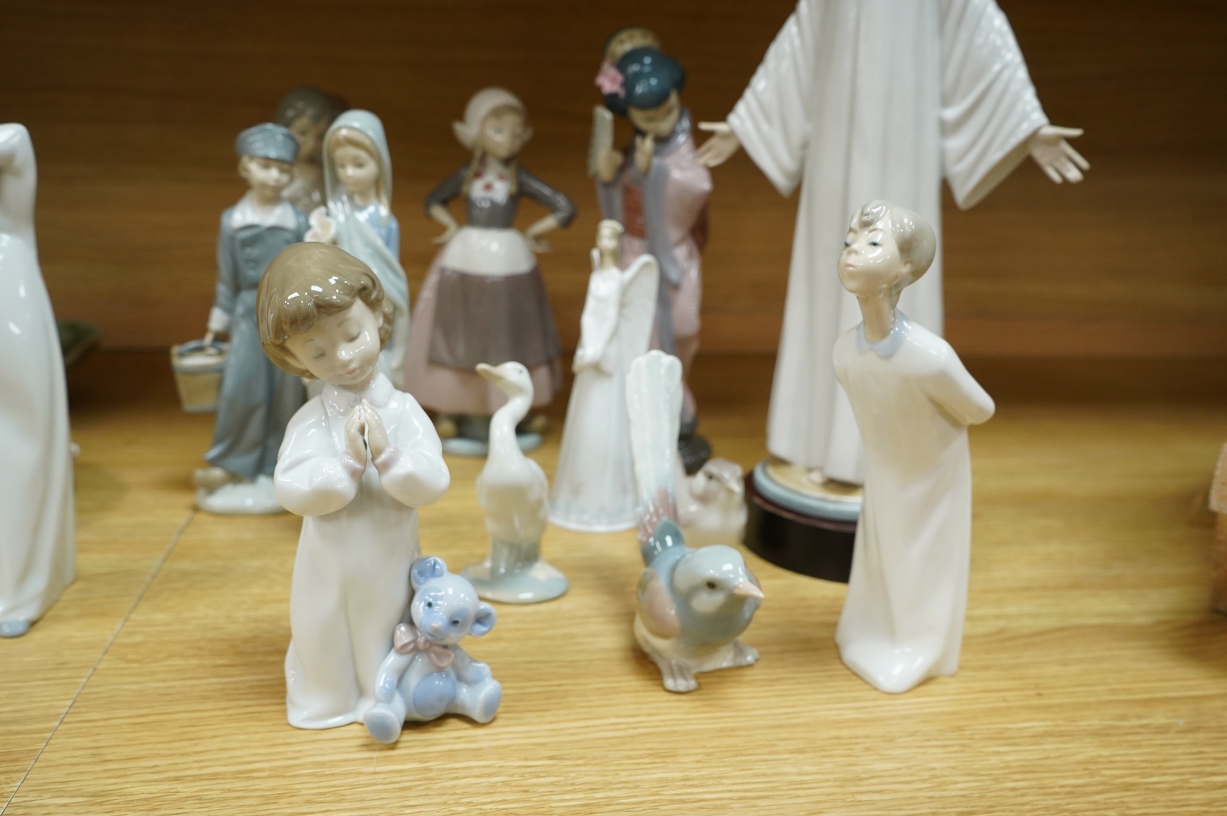 A group of Lladro figurines including: a Japanese Geisha, a model of Christ, 3 birds, various children, an angel bell etc. (all boxed) (13)